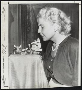 Expensive Lighter Set-Mrs. Karl Paley prepares to make use of a $5000 lighter set being shown at the American National Retail Jewelers display in the Waldorf Astoria Hotel. The set, known as a Heritage lighter, is made of 14-carat gold and set with 34 diamonds and 14 rubies.