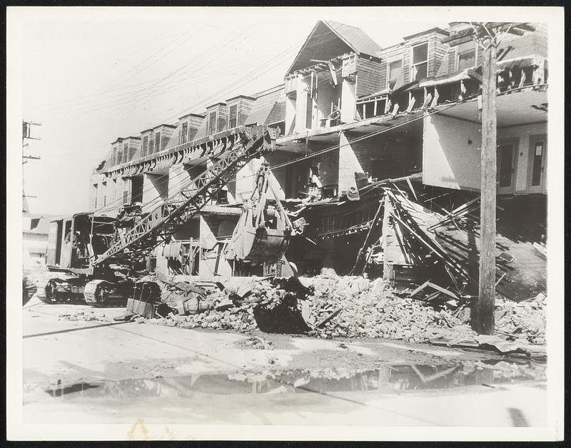 Compton, Calif., Continues Search. Photograph made in Compton, Calif., where wrecking crews continue their search for bodies under the debris. Sixteen persons lost their lives in the city, and it is feared more will be recovered. This scene shows a steam shovel removing the fallen walls of the Arande Hotel there.