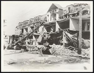 Compton, Calif., Continues Search. Photograph made in Compton, Calif., where wrecking crews continue their search for bodies under the debris. Sixteen persons lost their lives in the city, and it is feared more will be recovered. This scene shows a steam shovel removing the fallen walls of the Arande Hotel there.