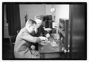A boy sitting next to a man using an unidentified device