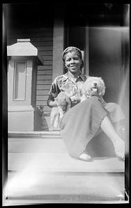 Constance Miller sits on a porch holding a dog and a cat