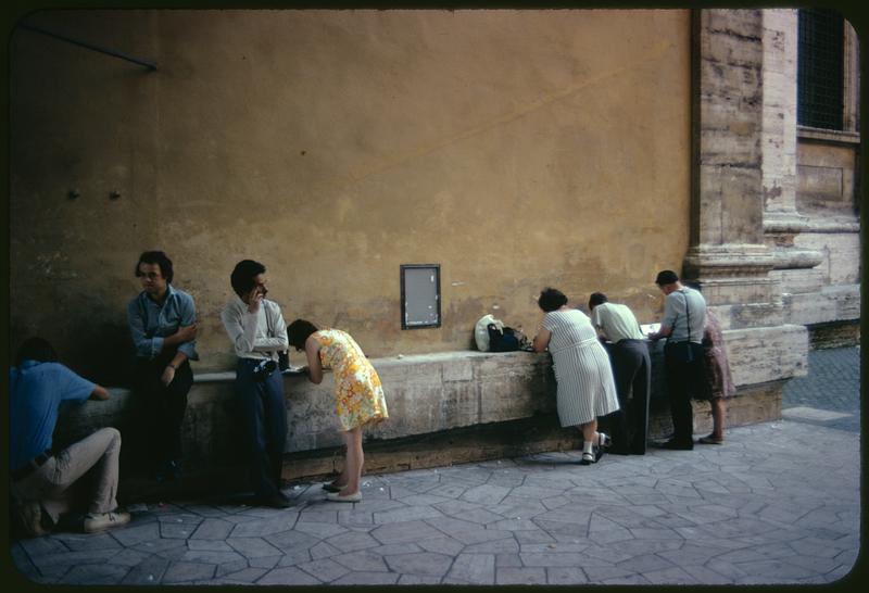 People leaning against ledge along exterior wall, Rome, Italy