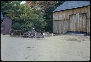 Woodpile and costumed woman next to barn, Old Sturbridge Village, Sturbridge, Massachusetts