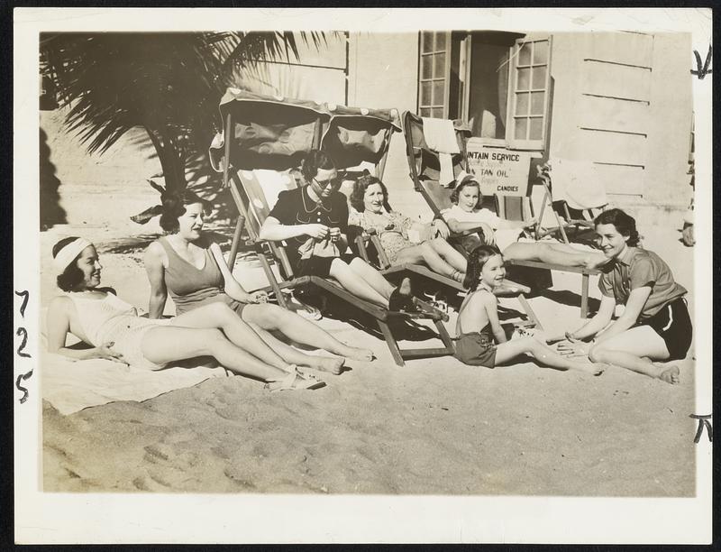 No Sand Trap Worries for Them. But even though these golf widows didn’t follow their husbands in the $10,000 Miami Biltmore open tournament, they got plenty of sand and sun on the beach at the hotel pool. Left to right are Mrs. Paul Runyan, Mrs. Jimmy Thompson, Mrs. Ralph Hutchinson, Mrs. Frank Walsh, Mrs. Lawson Little, Mrs. Densmore Shute, and out in front is little Nancy Shute, four-year-old daughter of the P.G.A. champion.