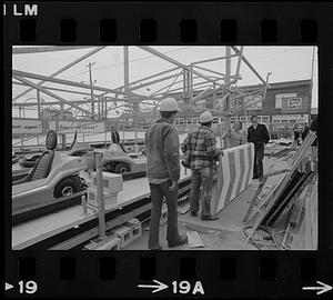 Workers at Le Mans Speedway construction site, with go-karts on track