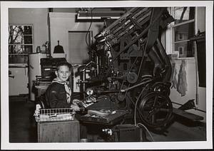 Boy Scout, Richard Reeve, shown in front of a printing press at the Sharon Advocate