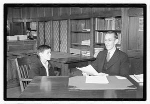A boy sitting next to a man