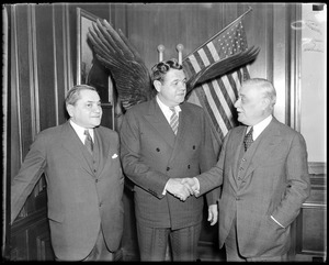 Jacob Ruppert, Yankee owner, shakes hands with Babe Ruth, while Braves owner Emil Fuchs looks on, after sale of Ruth to Braves