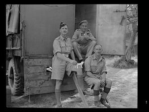 Men in uniform seated on truck