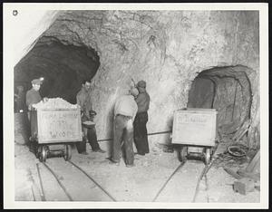 Where New Gold "Strike" was Made. Here's an interior view of the "Silver Queen" mine, 500 feet from the top, where a rich gold-bearing ledge has been found. The mine, on Soledad Mountain at Mojave, Calif., now is the center of a new "Gold Rush" from all parts of the west. More than $3,000,000 has been offered for the mine, but the owners refuse to accept. In this picture, taken Dec 3, workmen are shown loading one of the cars with some of the "Pay Dirt".