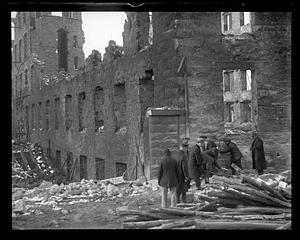 People examining debris after a disaster, possibly a fire