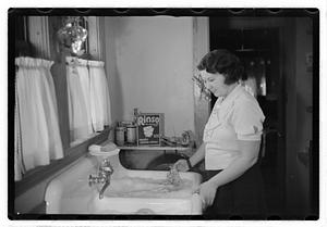 A woman at a sink full of laundry