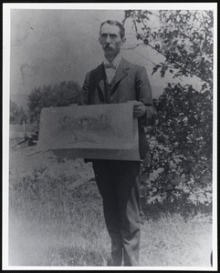 Young man holding a large paper, possibly a large map or blueprints
