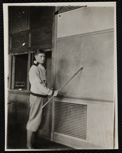 Young man with pointer at blackboard