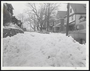Grampian Way, in the Savin Hill section of Dorchester, snowed in since Friday's storm, still serves as an open-air parking lot for stalled cars. The cars prevented plowing and today's snowfall added to the problem there and all over Boston.