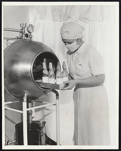 Infant Feeding Service Organized. Chicago- Miss Elizabeth Blaylock placing filled bottles in the sterilizer at the newly organized Infant Feeding Service here.