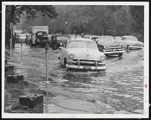 Torrential Rains today made wide rivers out of Boston streets such as Charles St. at left. However, nothing could deter the loyal Red Sox fans (right photo) who waited at Fenway Park for today's game with the Yankees. It was later postponed. They are George Christensen, Charlie O'Brien, both of Weymouth, Dan Tintindo of East Boston and Ralph Lucci of Everett. The Boston Weather Bureau said 2.08 inches of rain fell in the area.