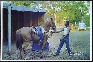 Charles Jackson with his horse Trigger in front of hay shelter