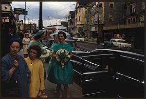 Women with flowers standing on sidewalk by cars, Jamaica Plain, Massachusetts