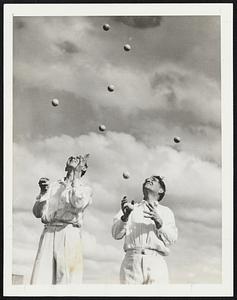 Nine Balls at Once. Wallace (left) and Ossie Delroy demonstrate their star stunt of juggling nine balls at once. They assert this is the first time the nine-ball stunt has been done in Australia. Each must have one ball in his hand, contrary to the assumption that all nine can be in the air simultaneously, Wallace, 18, has been a juggler for five years.