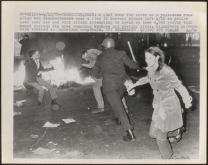 A girl runs for cover as a policeman runs after two demonstrators