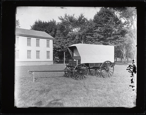 Covered wagon on display outside a large brick building
