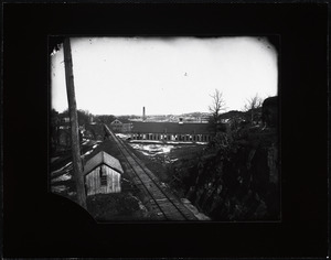 Winter scene with railroad tracks, industrial buildings, and houses