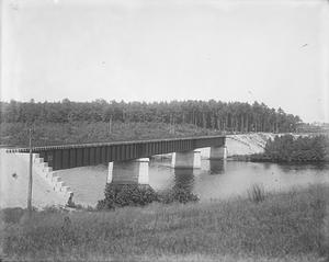 Bridge Road close to side bank, with man on bridge and town in distance
