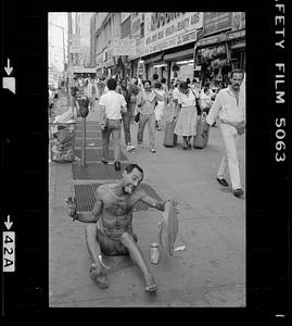 A man on the ground of a busy sidewalk