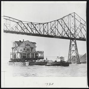 House Moving- This three storied. 150 ton former Coast Guard lighthouse barracks is being towed under Carquinez bridge in Vallejo, Calif., on its way upstream to Elliot Cove, where the owner plants to make it into a dance pavilion and restaurant. The 28 room house was transferred from pilings in Mare Island channel to a barge, which is seen carrying it to its new location.