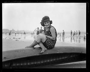 Woman in bathing costume sitting on a canoe