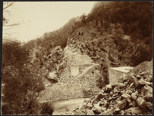 View of river with pile of quarried rocks on right side near what appears to be a newly constructed stone culvert or bridge support