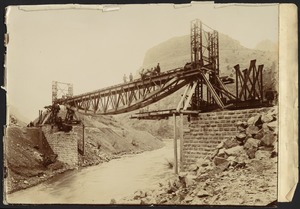 Construction of steel bridge over a river, men working on top