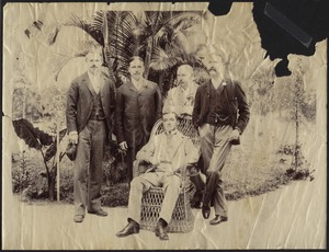 Five men posing in front of palm trees; one young man sitting in wicker chair, JGC second from left