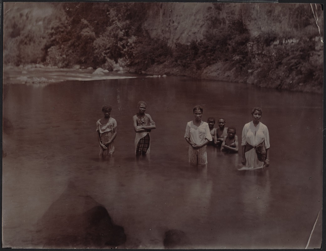 Young women and children, possibly of African decent, bathing/standing in a river