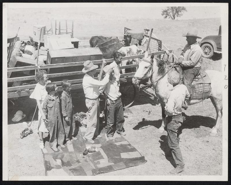 Two families make merry in spite of the circumstances as they wait for the sun to set at their camp along the Missouri river before resuming their journey. They are members of the Perry Kotterman and Lloyd Taylor families who are moving their cattle and possessions from Trail City, S.D., in the drought area. They cover about 30 miles a day on their slow journey.