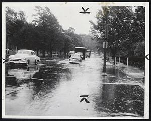 Cars Move Slowly along Charles St., between Boston Common and Public Gardens, in downtown Boston during storm. The busy thoroughfare was flooded to curb depth.