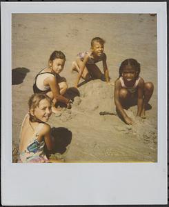 Polaroid of Jamie, Sarita, April and Laurraine playing in the sand during a beach field trip