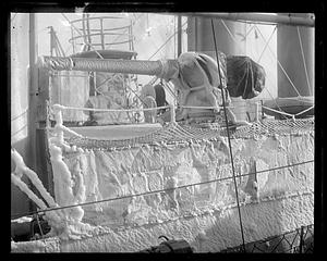 Ice covered side of a ship, possibly a naval gun on top