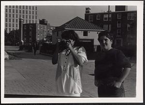 Two people, one with a camera taking a photograph at Newtowne Court