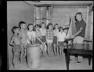Unidentified man with sailboat model and group of children