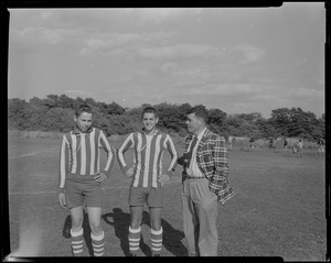 Two soccer players with man in suit