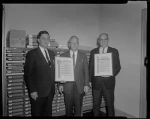 Victor Adams with two men holding framed certificates