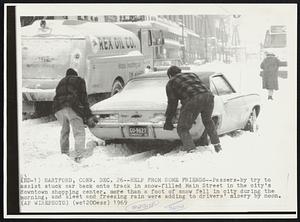 Hartford, Conn. - Help From Some Friends - Passers-by try to assist stuck car back onto track in snow-filled Main Street in the city's downtown shopping center. More than a foot of snow fell in city during the morning, and sleet and freezing rain were adding to drivers' misery by noon.
