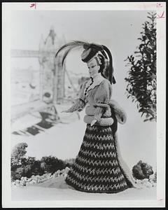 A Bustle, Plumed Hat and Chin-High Lace Collar All Add Up to the Elegance of the Victorian Era. The sweeping skirt is knitted in gleaming stripes of gold metallic "Knit-Cro-Sheen" and yarn in a deep rich green. The puffed sleeved bodice with its hip band and trailing bustle is done in a paler shade of green. She's a masterpiece of a gift for that very special lady-like little girl. Free instructions are available by sending a self-addressed, stamped envelope to the Needlework Editor of this newspaper along with your request for Leaflet PK 3787.