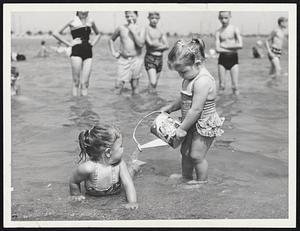 Pleasure Bay Cooler is administered to Donna Anastas, 20 months old, of Dorchester, by her sister, Elaine, 2 1/2 years, at the South Boston beach. The young ladies were among thousands who repaired to beaches in record heat.