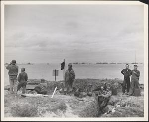 Navy beach party eye the skies for enemy raiders after setting up communications and erecting beach markers on the Normandy coast