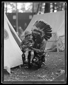 A man in Native American dress holding a little girl