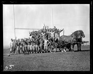 A group of football players posing on and around a horse drawn cart