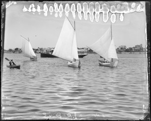 Charles W. Parker kayaking alongside three sailing dories with "Herald" in background